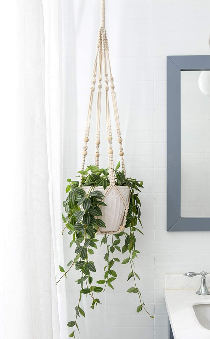 A white plant hanger hanging gracefully in a bathroom.