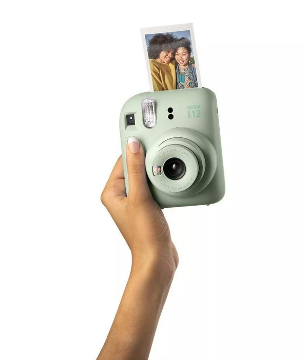 An instant camera held in hand, printing a picture of a smiling couple. Featured in a shopping guide