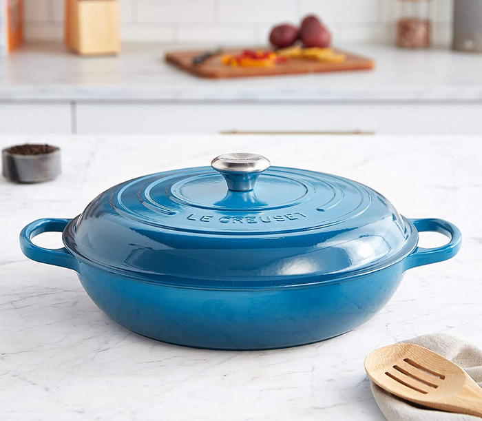 A blue Le Creuset braiser resting on a kitchen counter, ready for use.