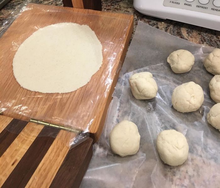A reviewer's photo showing a tortilla perfectly flattened by the press, with balls of dough placed beside it.