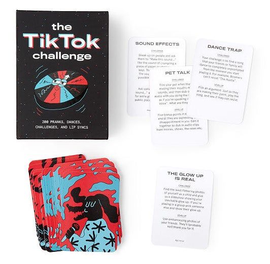 A card game displayed with sample challenges and the sleek black box it comes in, which reads