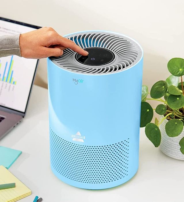 A model powering up a blue air purifier to bring in fresh air.