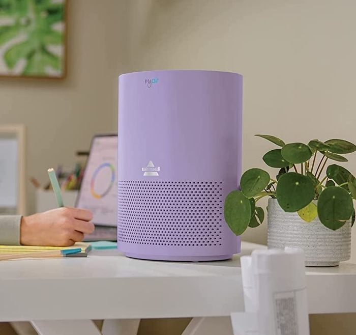 A purple air purifier placed on a desk, adding both charm and freshness to the space.