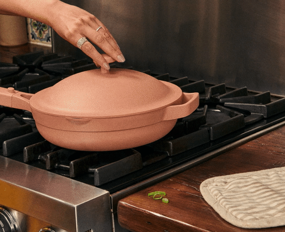 GIF showing someone removing the lid from the pink Always Pan and lifting out a steamer basket filled with dumplings.