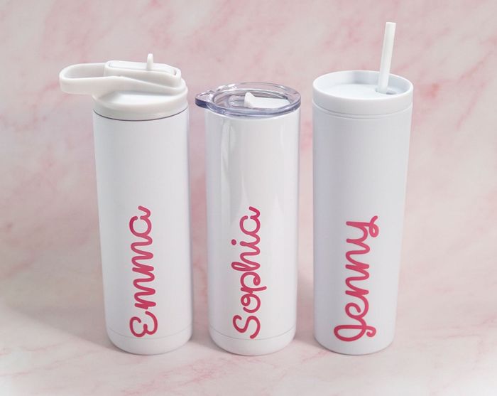 Three personalized white drink tumblers, each bearing the names Emma, Sophia, and Jenny in pink text, with different lid options for each.