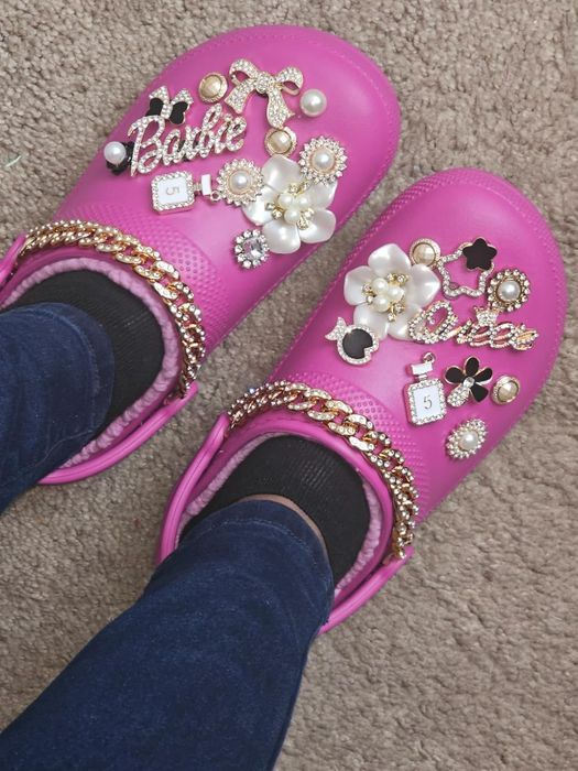 Pink clogs decorated with a variety of charming decorative charms, pearls, and more