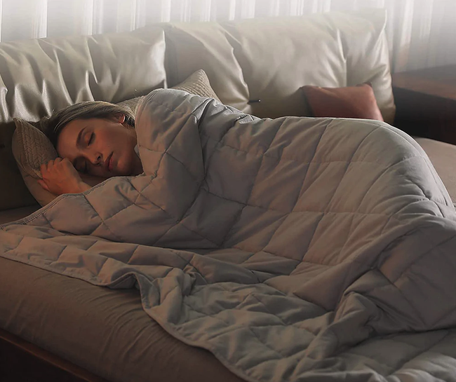 A model lounging under a light grey quilted blanket