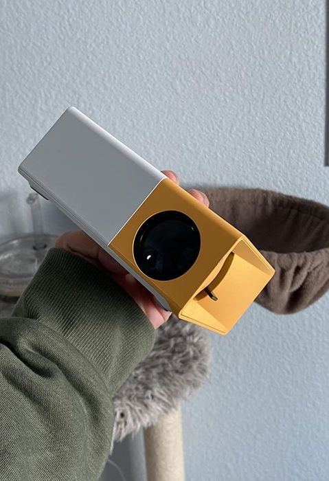 A reviewer holds up the compact yellow and white projector.