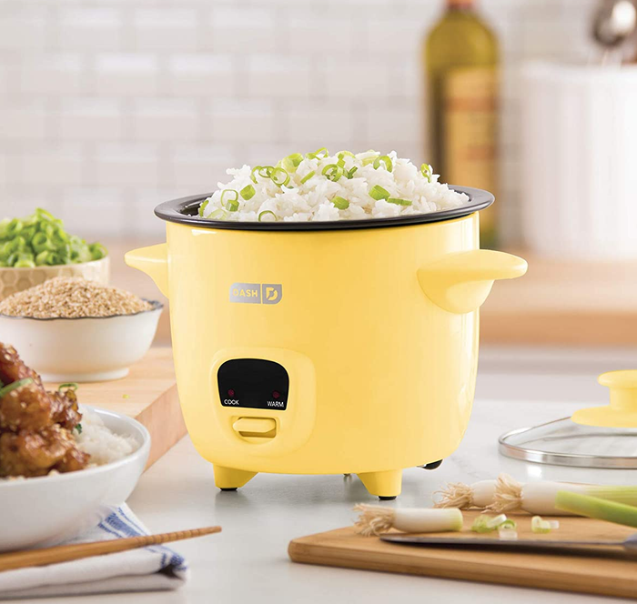 The yellow rice cooker sitting on a kitchen counter, ready for action.