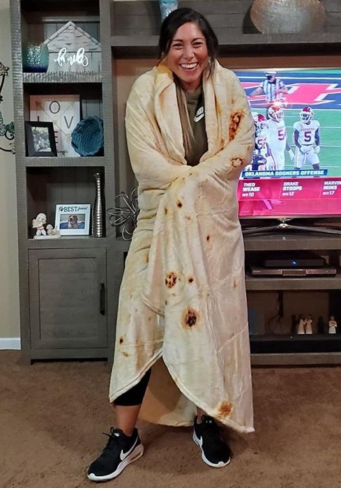 A reviewer snuggles up in the cozy burrito blanket