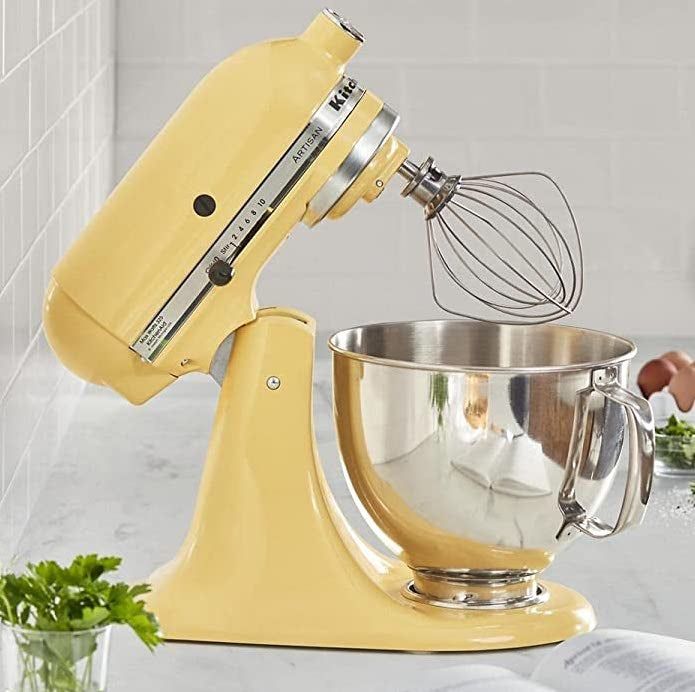 the yellow stand mixer positioned on a counter with its head tilted backward