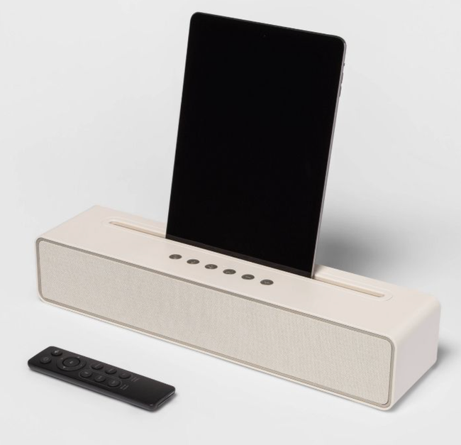 A beige speaker holding a phone, offering a seamless way to enjoy music or take calls.