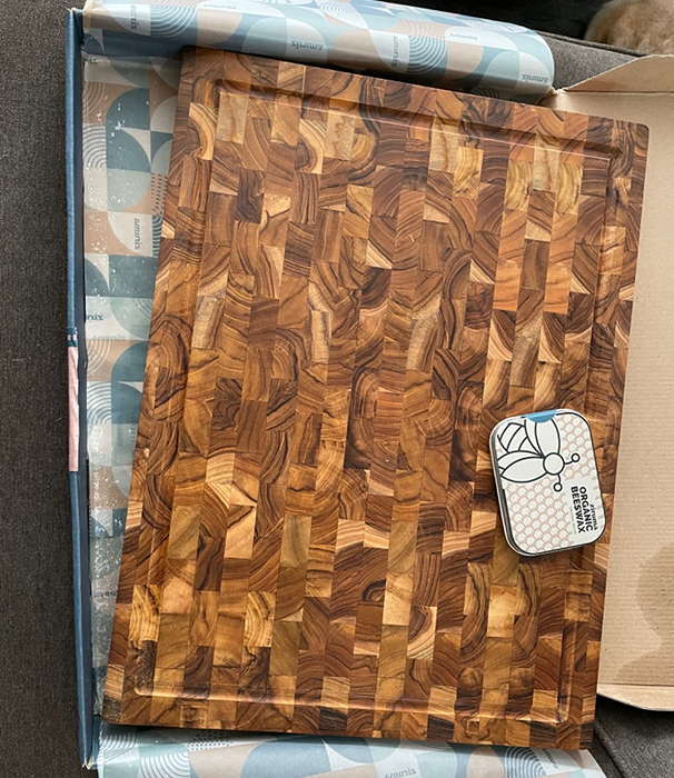 A photo of the cutting board in its box, accompanied by a container of wax to maintain its shine.