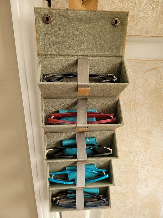 A reviewer’s photo of the organizer hanging, with sunglasses neatly stored in each compartment.
