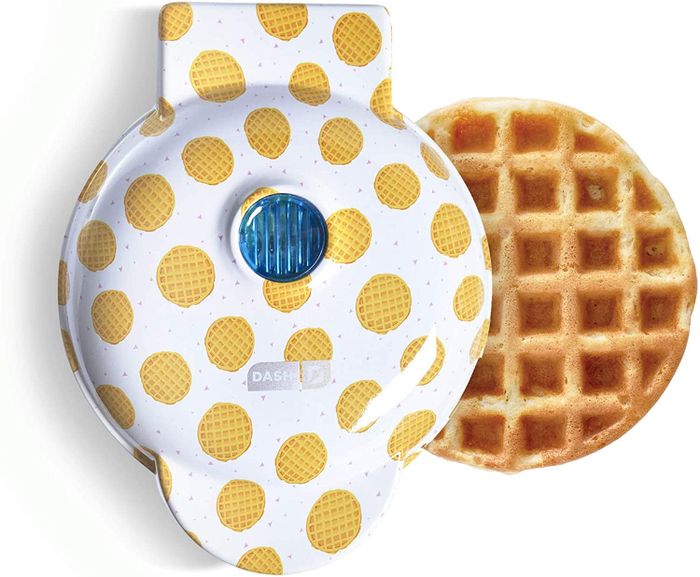 The waffle-print waffle maker placed next to a freshly made waffle.