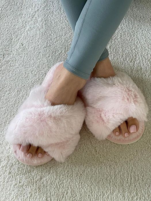 A person wearing fluffy slippers and light leggings, displaying a pink pedicure. Featured in a shopping article