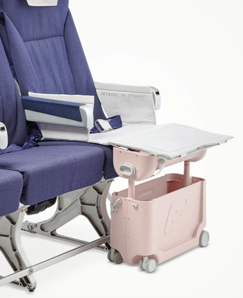 The suitcase placed in front of a seat that resembles an airplane chair, lifted to create a leg rest for kids, making the seat more comfortable for them.