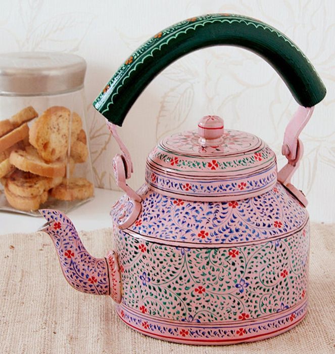 The pink painted teapot placed beside a jar of cookies.