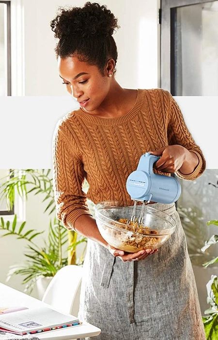 A model demonstrating the use of the blue hand mixer to blend a batch of cookie dough.