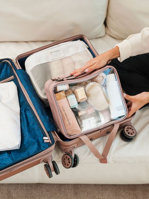 a model placing the clear makeup bag into a suitcase
