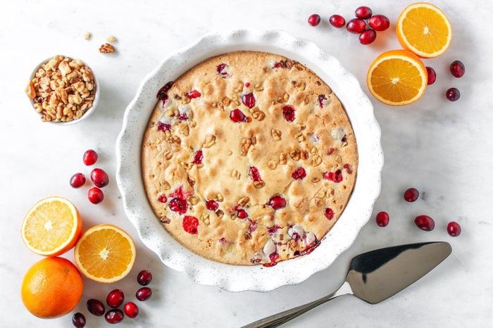 An overhead shot of the pie dish holding a fruity, baked dessert, surrounded by various fresh fruit ingredients.