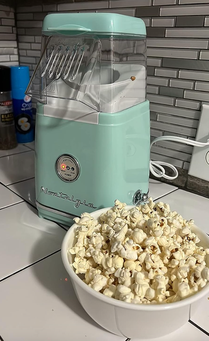 A small blue electric popcorn maker with a clear top where the freshly popped corn comes out.
