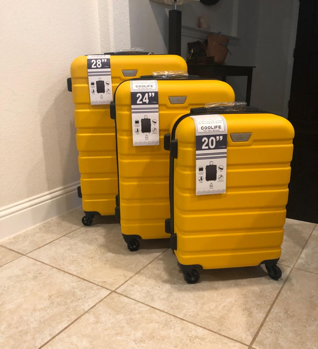 A reviewer's photo showcasing the three-piece luggage set in a bright yellow color.