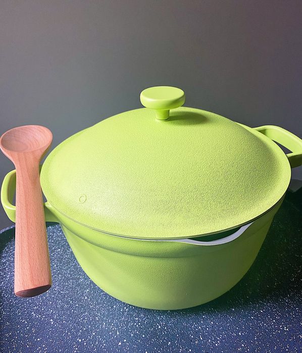 The vibrant green pot with a wooden spoon resting on its handle.