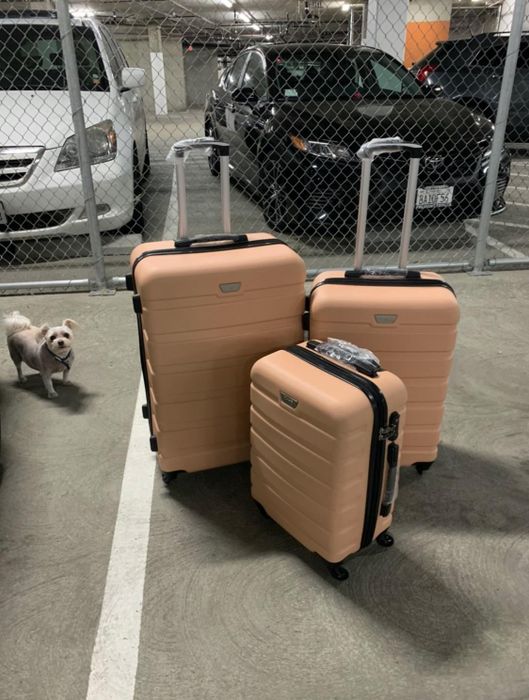 A reviewer's photo showing the three-piece luggage set in a soft nude color.