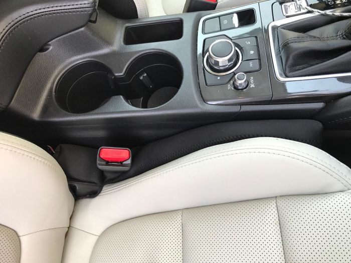 A black seat filler wedged between a car seat and the console