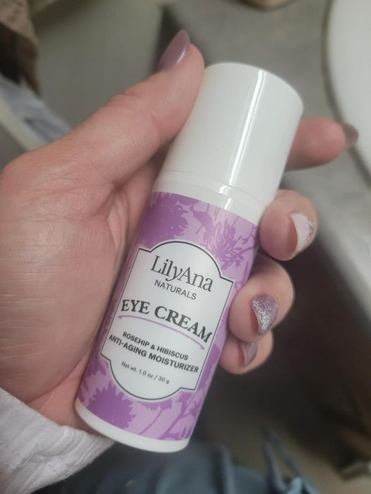 The reviewer is seen holding a bottle of eye cream.