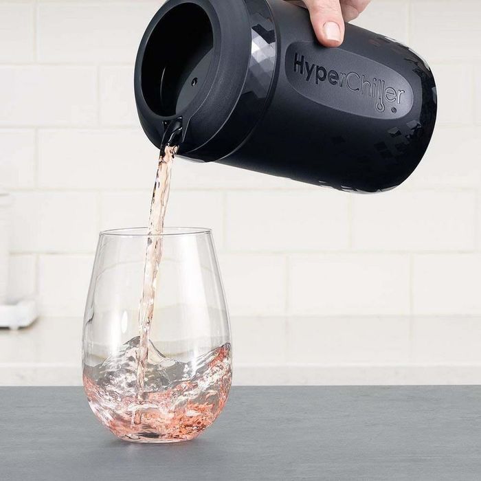 A hand pouring rosé from the HyperChiller into a glass.
