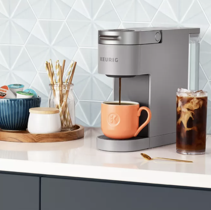 A slim gray Keurig dispensing a cup of coffee