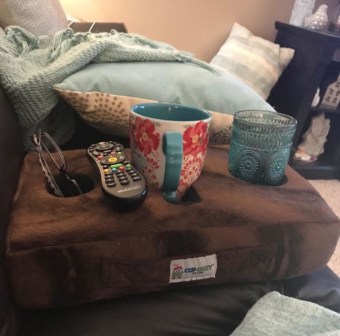 A brown cushion featuring three circular openings for cups and mugs
