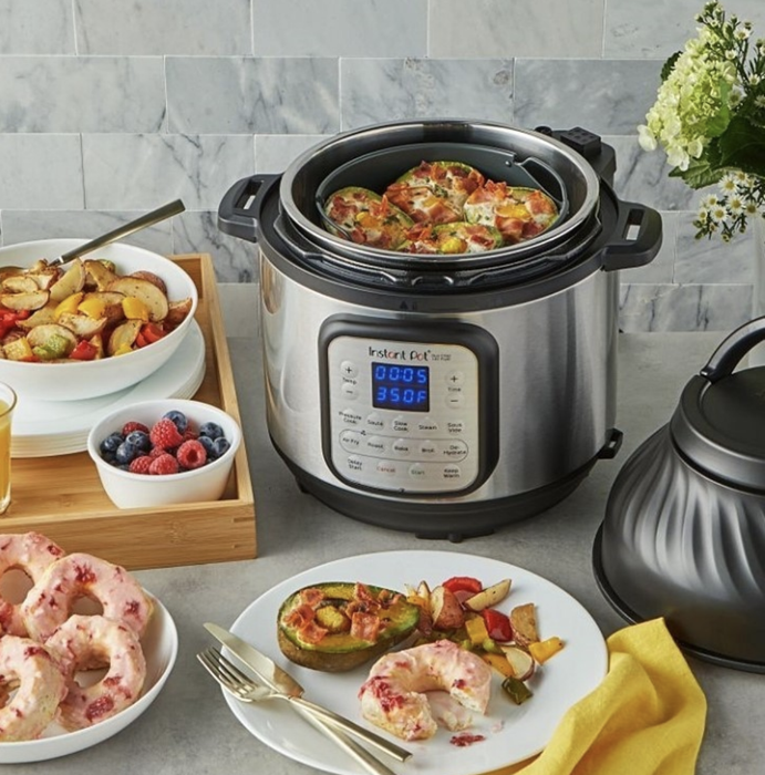 The Instant Pot, cylinder-shaped, with a control panel showing various settings and temperatures