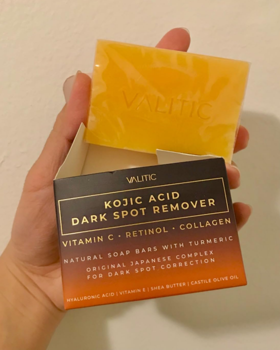 The reviewer is pictured holding both the soap bar and its packaging.