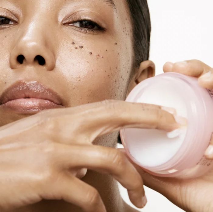 A person holding a jar of cleansing balm