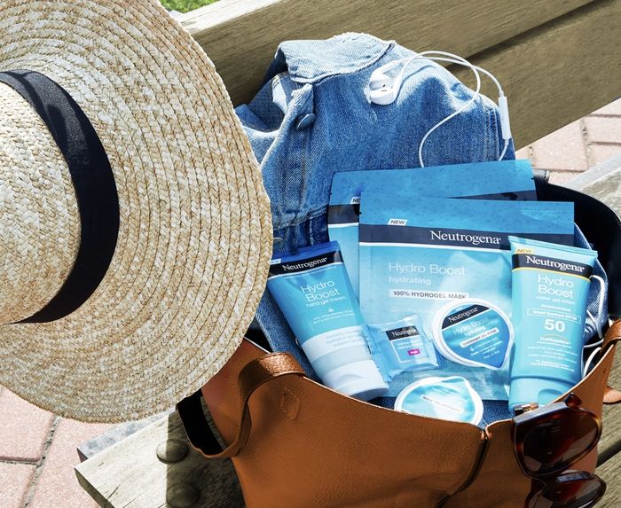 A beach hat and bag filled with a face mask, sunscreen, and a jean jacket