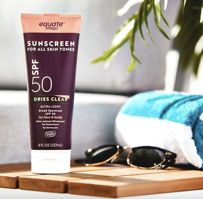 A tube of sunscreen lotion, a pair of sunglasses, and a beach towel