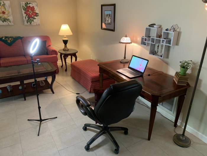 A lit selfie ring mounted on a tripod, aimed at a reviewer's desk setup.