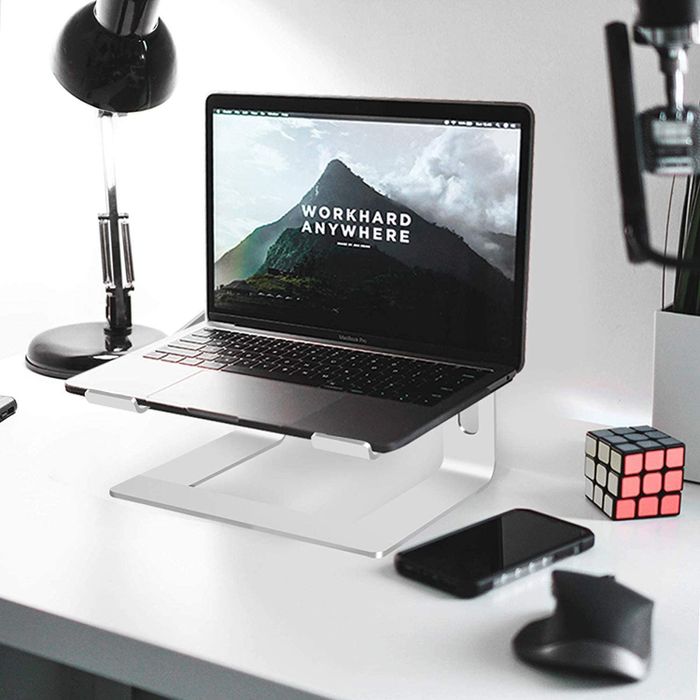 A laptop positioned on a stand atop a desk.
