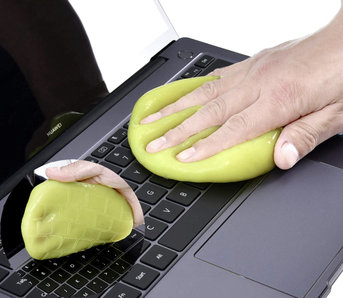 A model is using a yellow squeegee to extract crumbs from a Mac keyboard.
