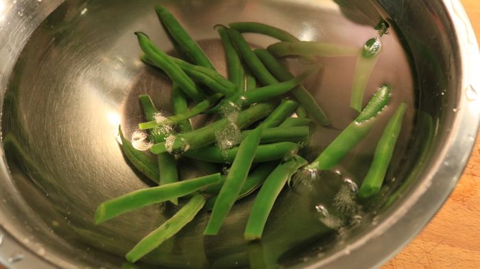 Green beans submerged in an ice bath.