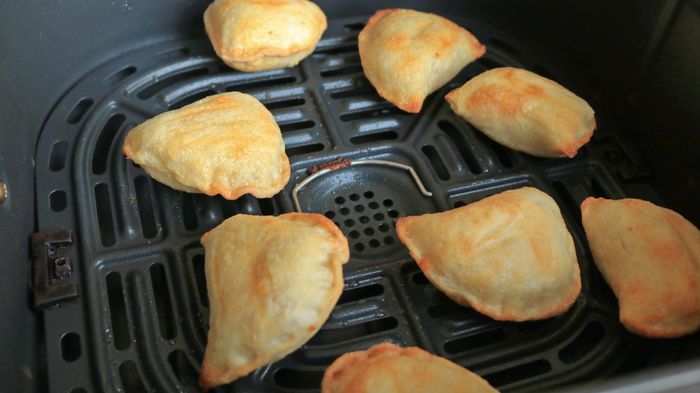 A basket filled with golden brown pierogi in the air fryer.