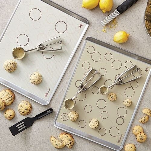 Two baking sheets with white silicone mats, featuring circular guides to perfectly space out cookies.