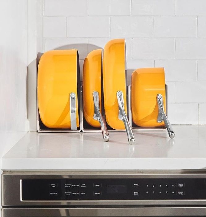 the nonstick pots and pans neatly arranged on a shelf in a vibrant marigold color