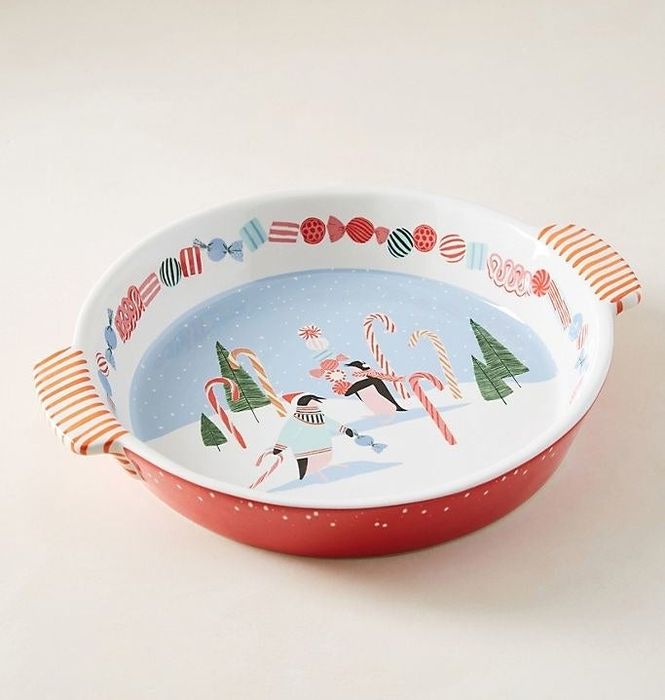A red pie dish with a white interior that depicts a serene winter scene, perfect for the season.