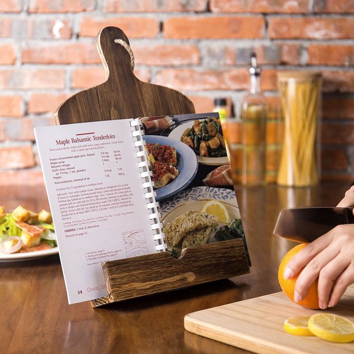 A rustic wooden cookbook stand that has a design similar to a cutting board.