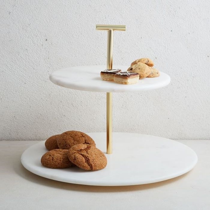 A two-tiered marble stand with circular surfaces and a brass pole running through the center.