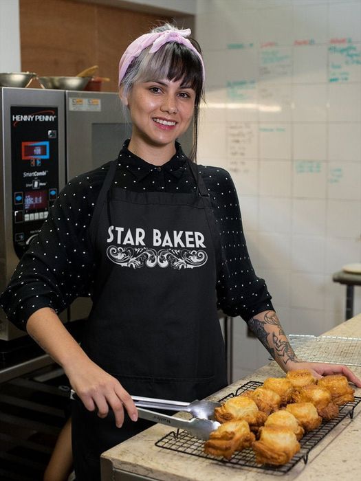 A model wearing a black apron with the words